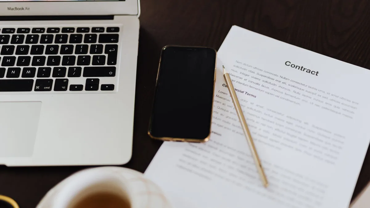 A smartphone, laptop, and a legal contract on a law firm desk