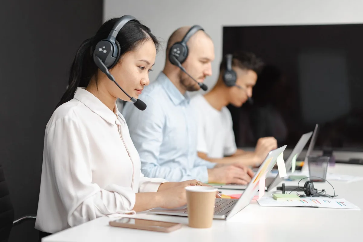 A person wearing a headset taking calls at a service desk where an AI voice agent handles overflow